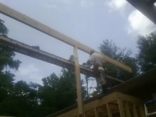 Carpenter setting a ridge beam over a new addition frame — Ice Dam Removal by Roofing Brothers in Ada