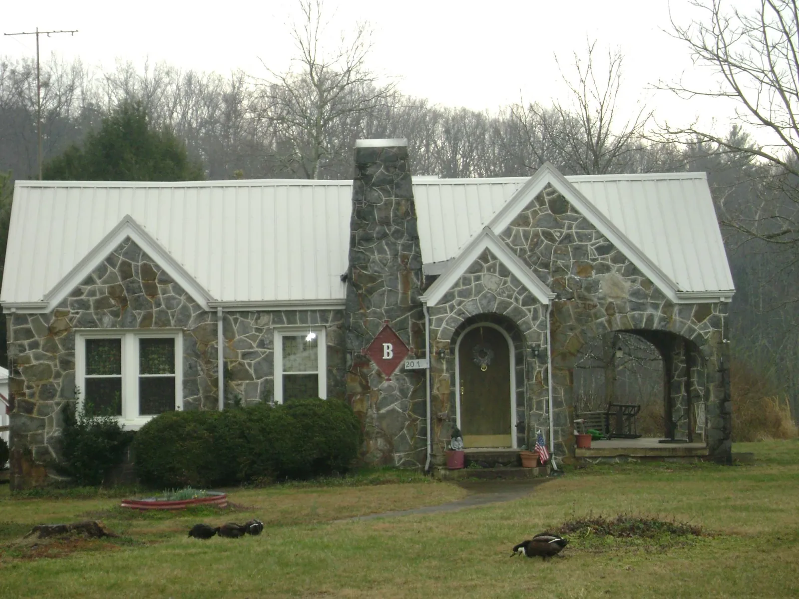 White metal roof on a stone cottage with steep gables in Ada